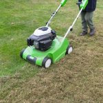 person dethatching moss lawn in a backyard